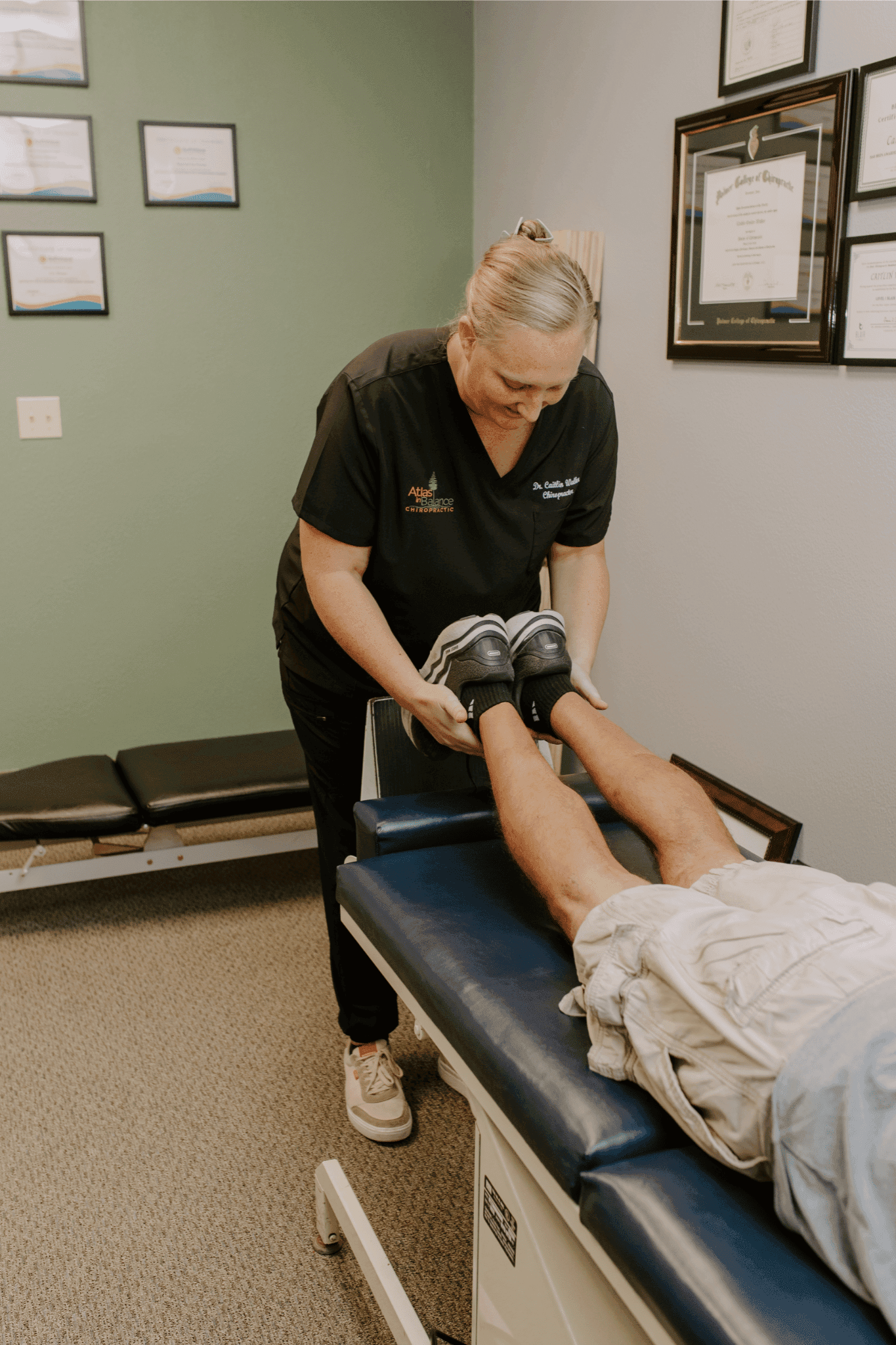 Oceanside chiropractor Dr Caitlin Walker performing routine assessment on an athlete whose laying down on a chiropractor table.
