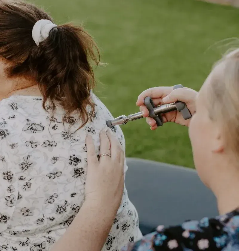 Dr. Caitlin Walker using a low-force handheld adjusting instrument, part of gentle headache care in Oceanside