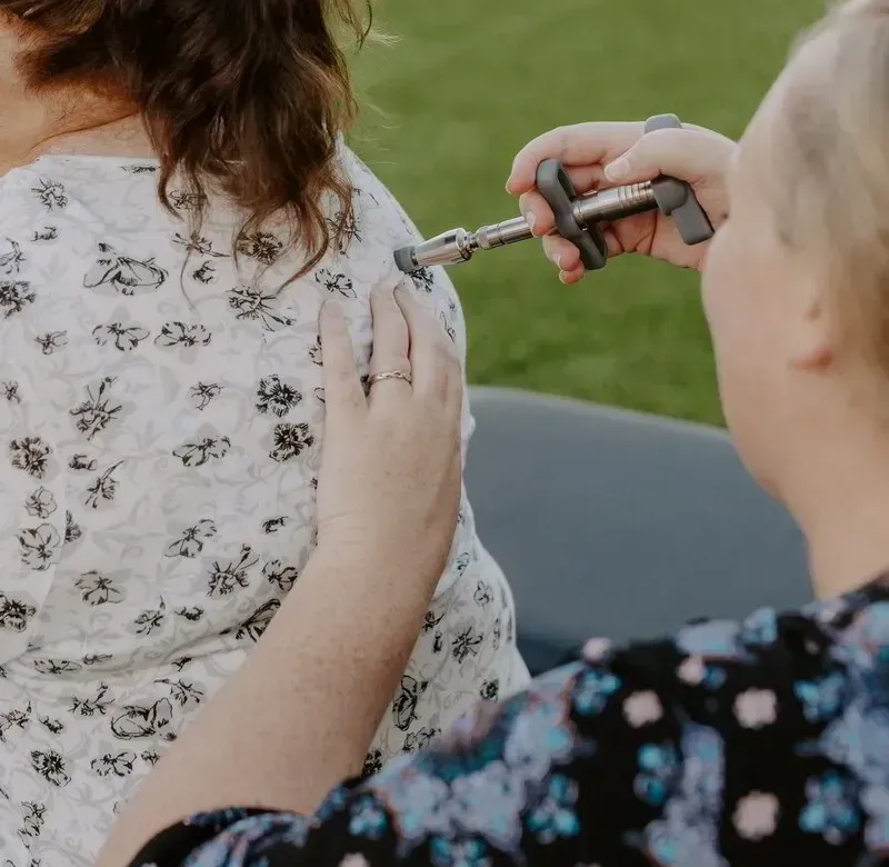 Dr. Caitlin Walker using a low-force handheld adjusting instrument, part of gentle care for menstrual cramps in Oceanside